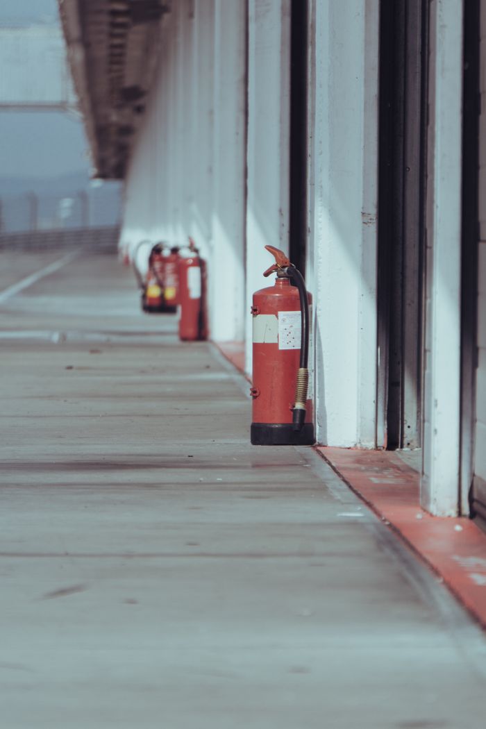 Multiple fire extinguishers lined up in an industrial outdoor corridor, emphasizing safety and preparedness.